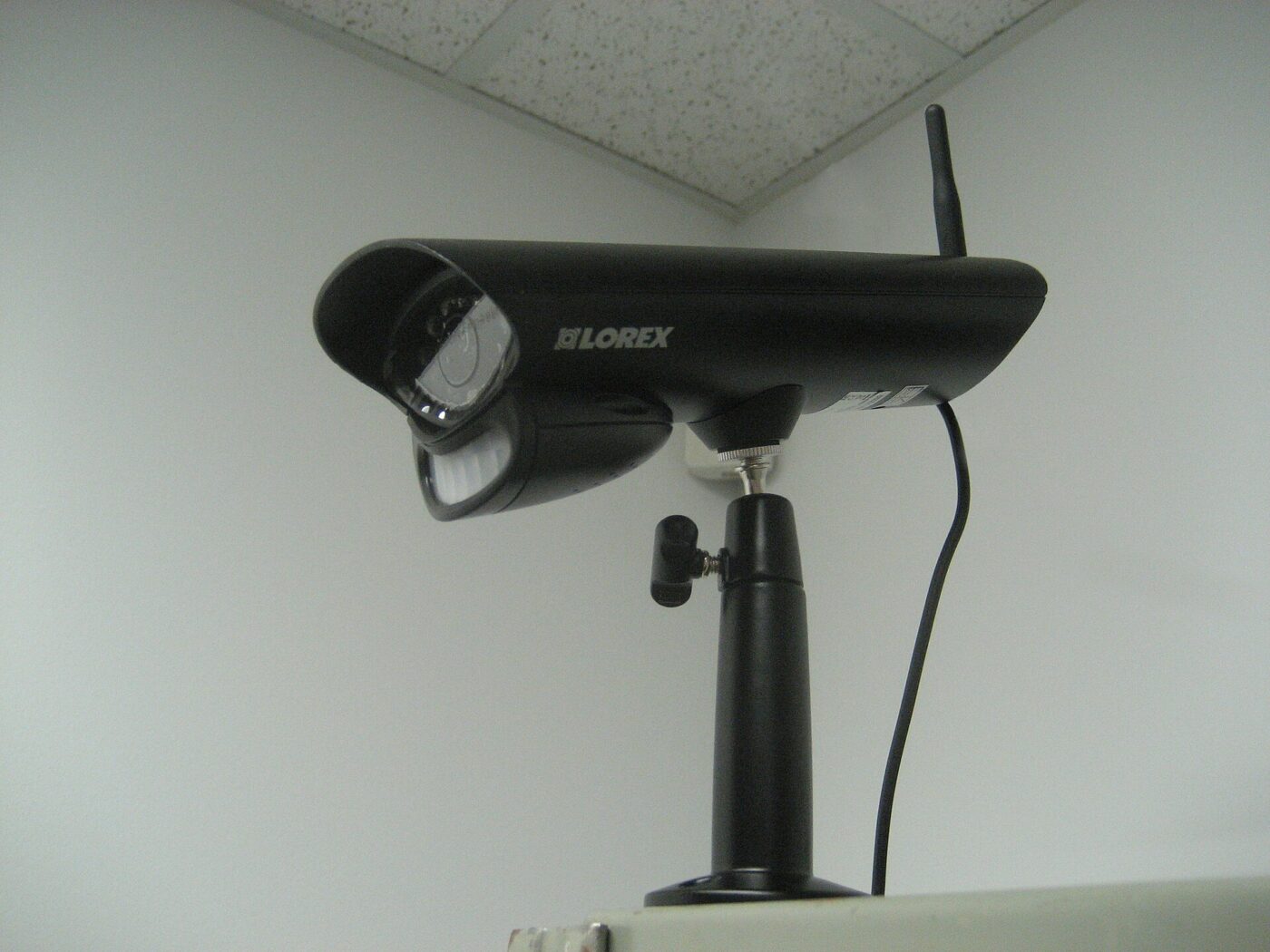 A wireless security camera with its antenna and mounting arm.