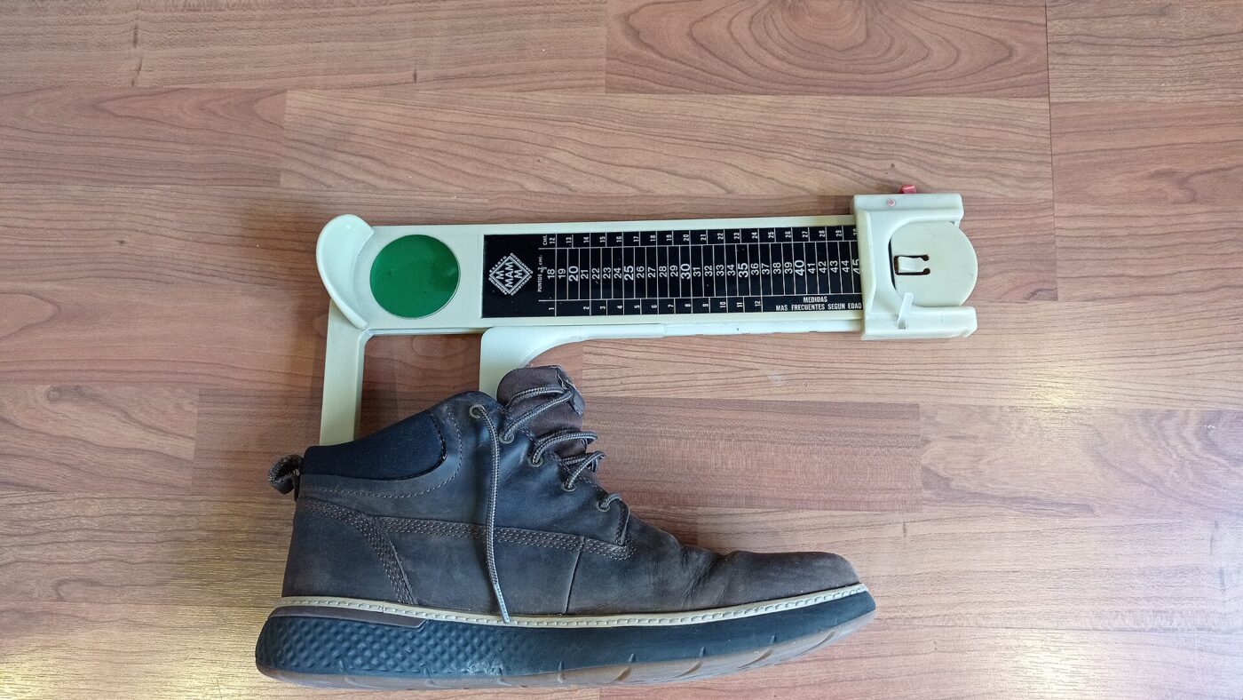 Measuring a shoe against a foot sizing device.