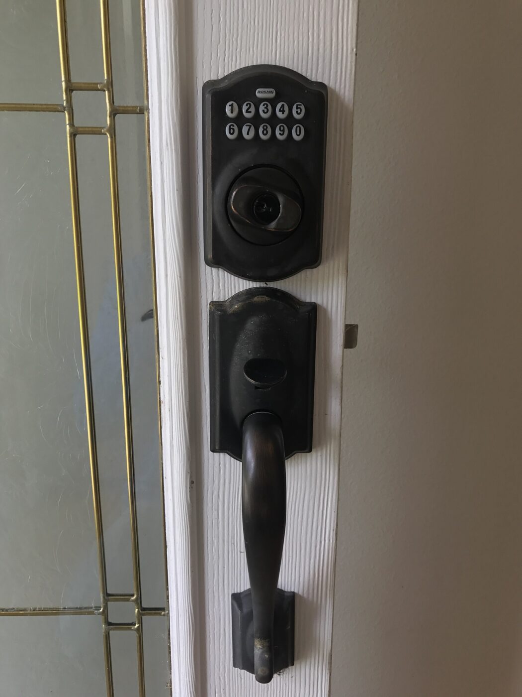Finished installation of a keypad deadbolt lock on a residential front door with a sidelight window.