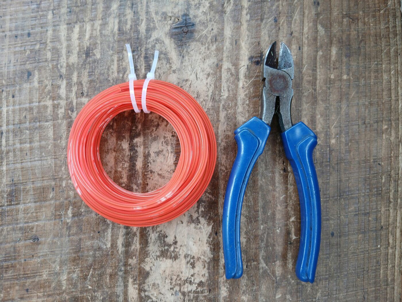 A coil of replacement trimmer line next to a pair of side cutters.