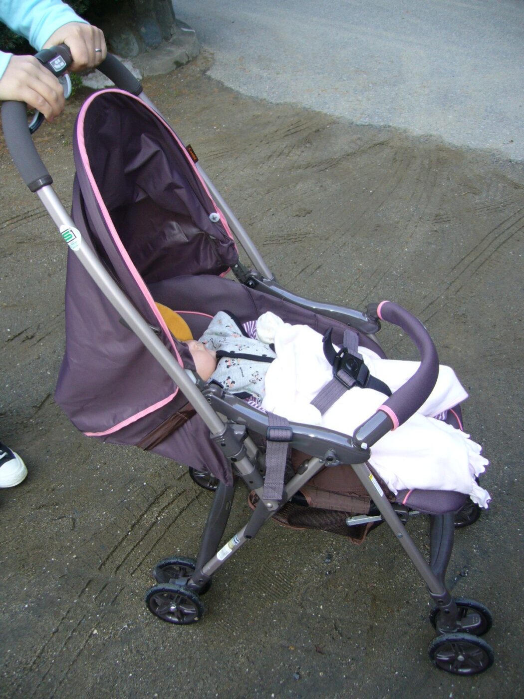 A lightweight stroller with a sleeping baby under a blanket.