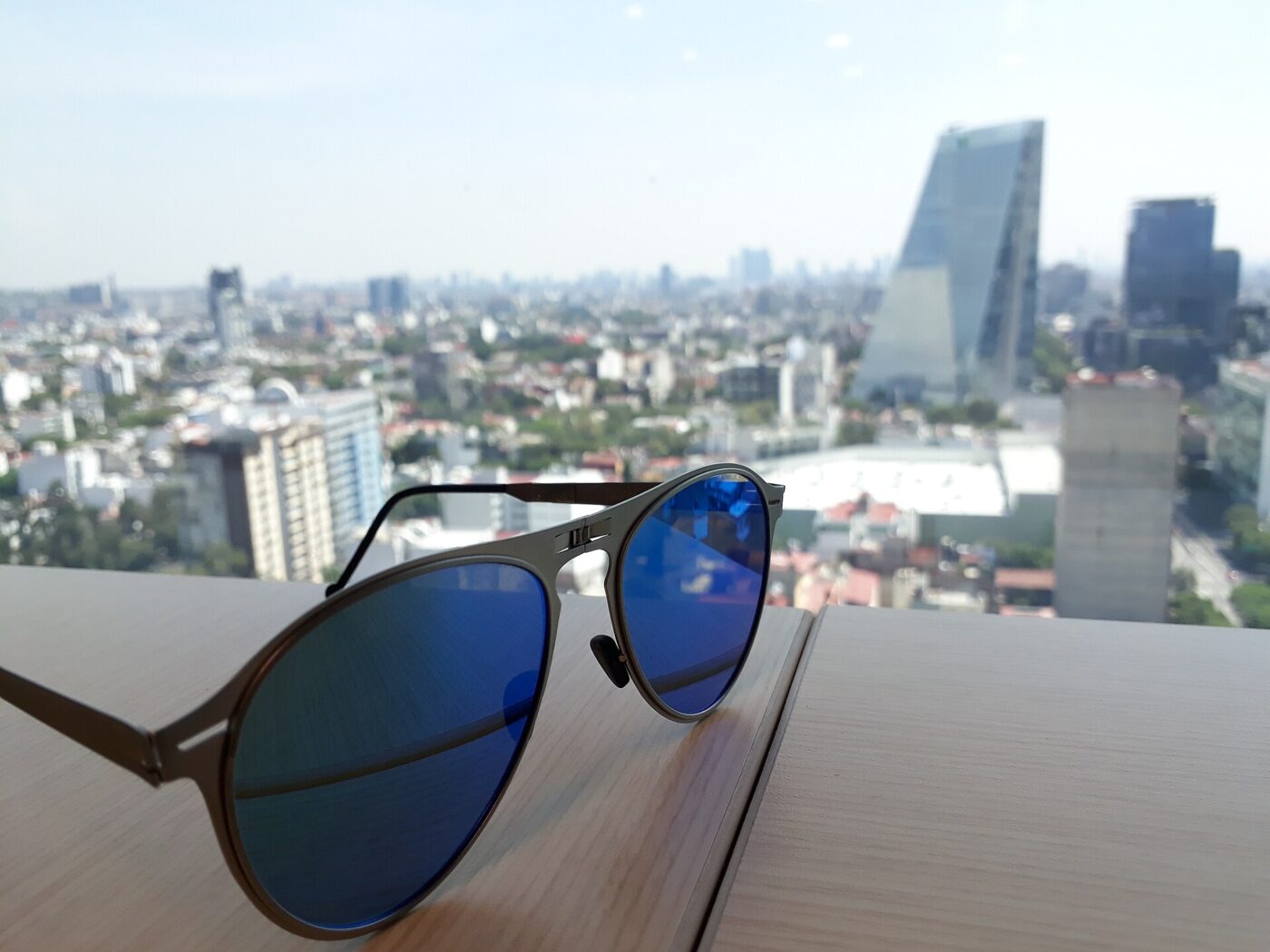 Sunglasses on a ledge above a city.