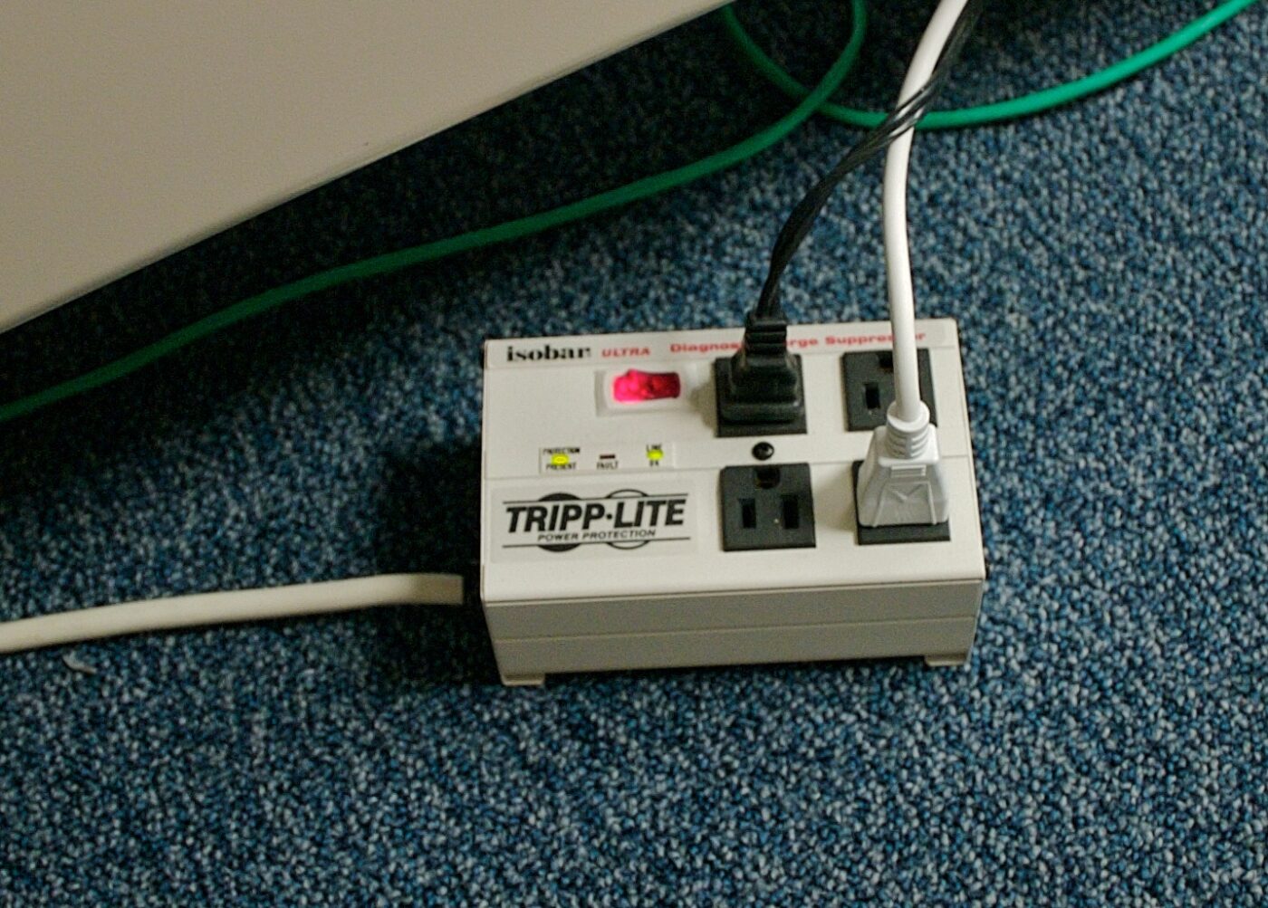 A beige surge suppressor power strip with indicator lights, plugged into cords.