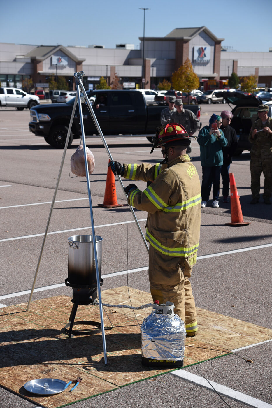 A firefighter in gear standing near a pot on a tripod stand outdoors.