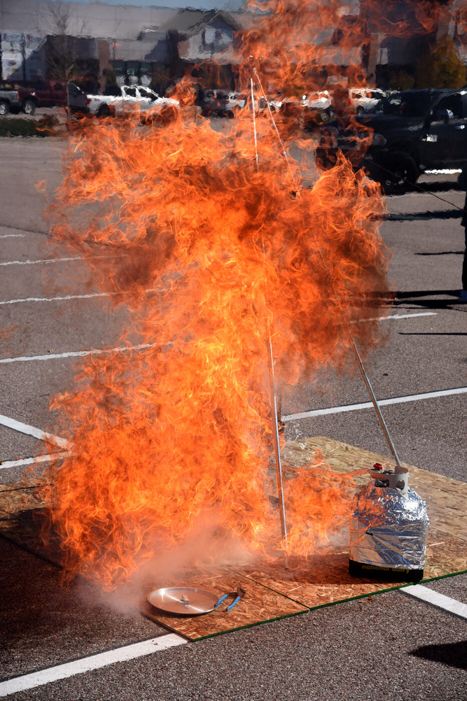 A burst of orange flame on the ground during a fire-safety demonstration.