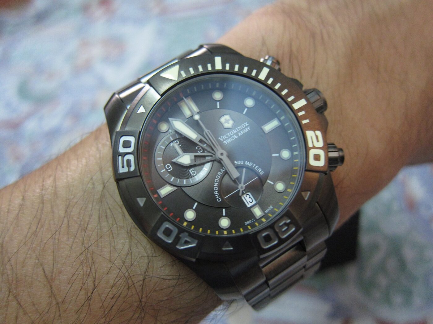 Close-up of a black-dial dive watch with a rotating numbered bezel on a person's wrist.