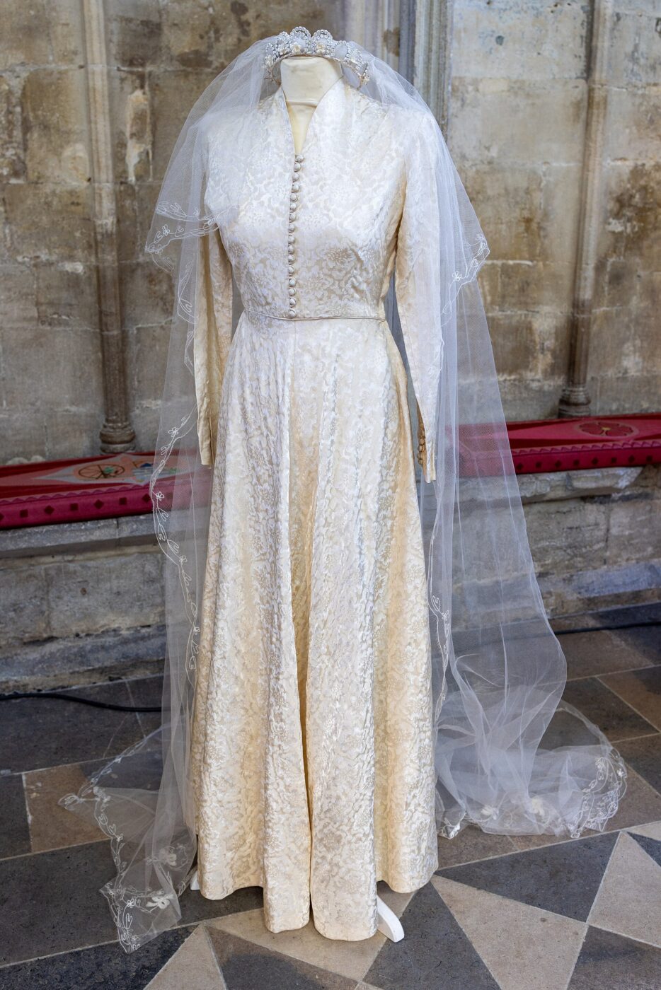 Vintage 1952 wedding dress and veil shown on a dress form, fabric visibly aged.