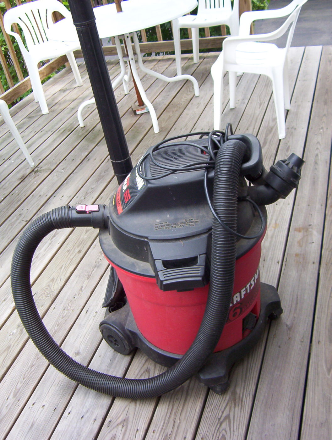 A red and black wet/dry shop vacuum with its hose attached.