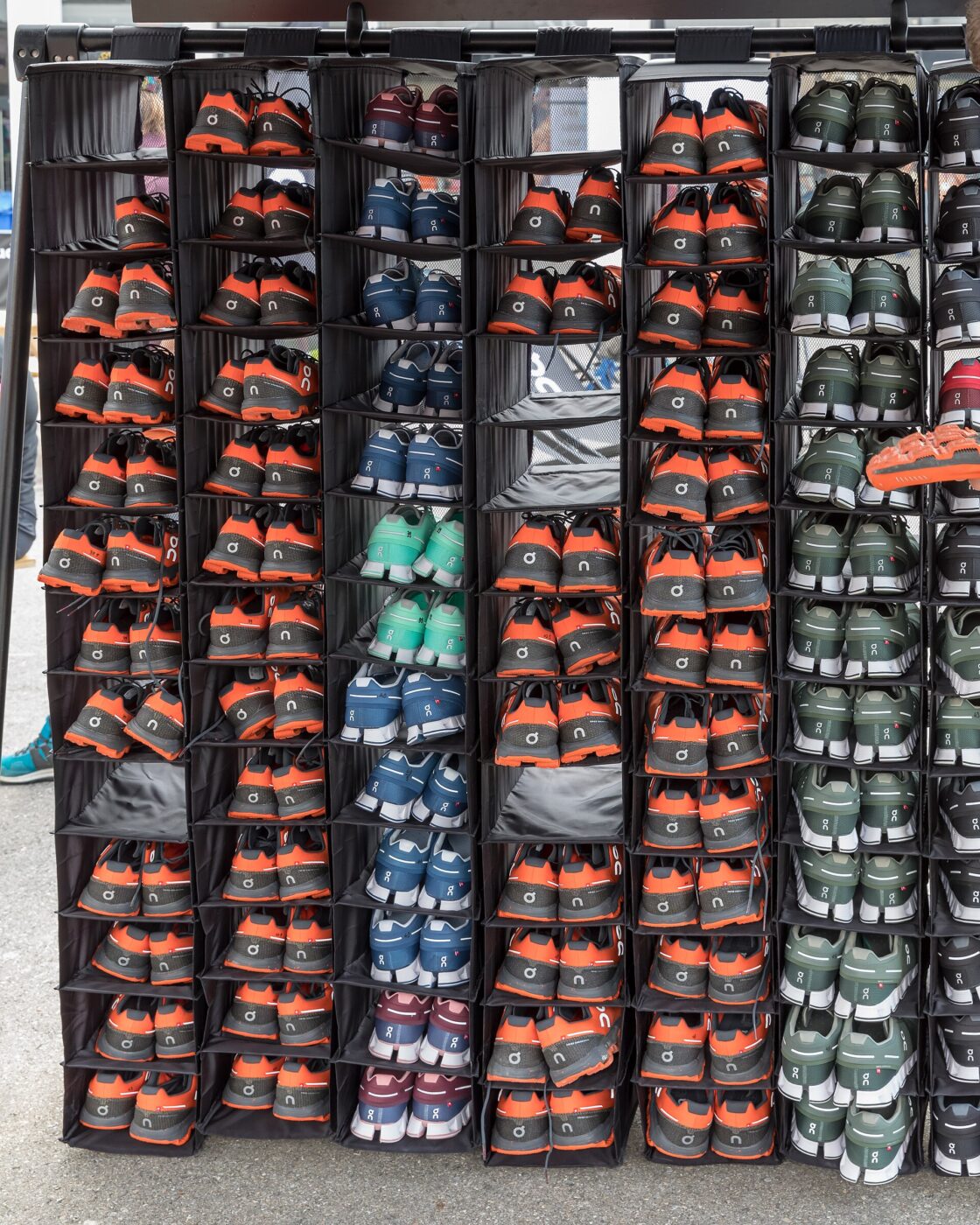 A wall of running shoes in boxes on display at a trade show