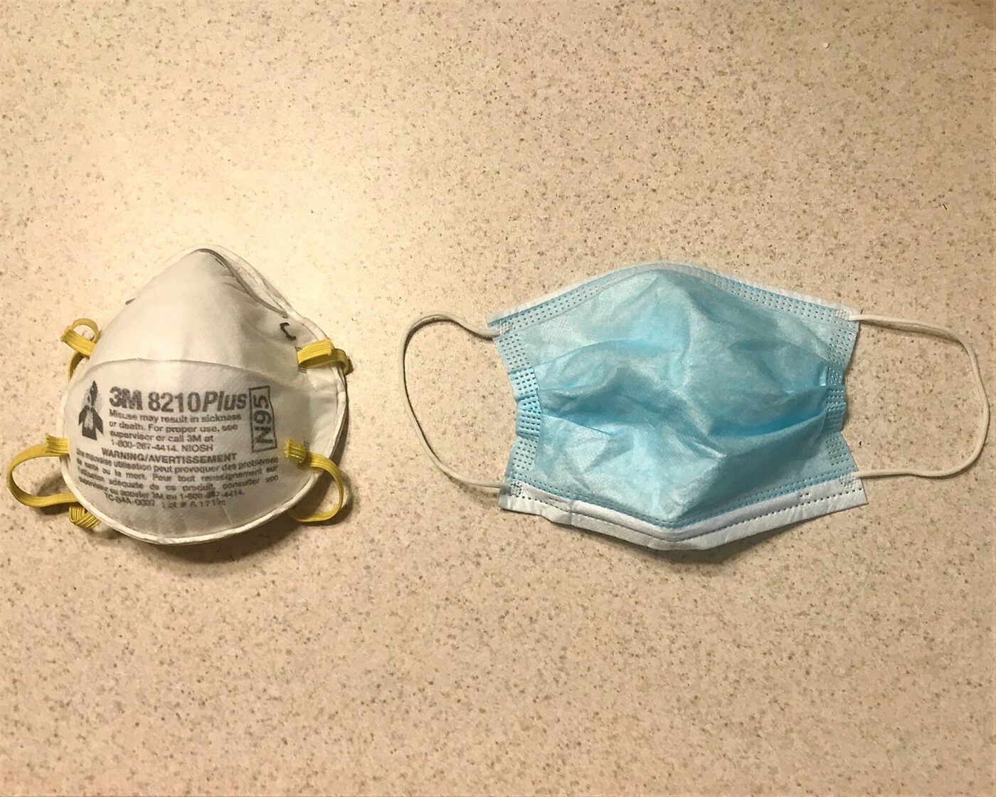 An N95 respirator next to a blue surgical mask